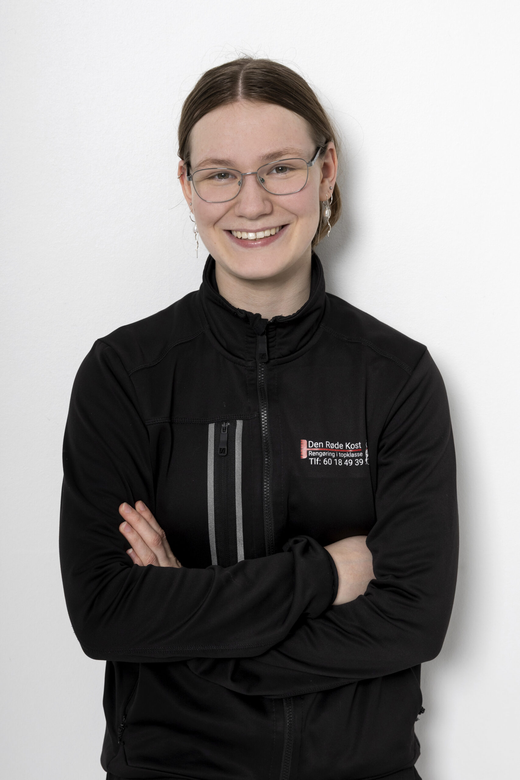 Smilende medarbejder i sort arbejdsjakke med logo